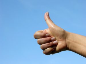 motivierende gehobener Daumen vor blauem Himmel