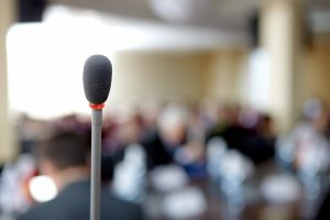 Mikrofon im Vordergrund Publikum verschwommen im Hintergrund