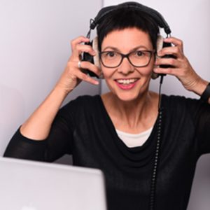 Brigitte Hagedorn vor Laptop mit Händen am Kopf am Kopfhörer
